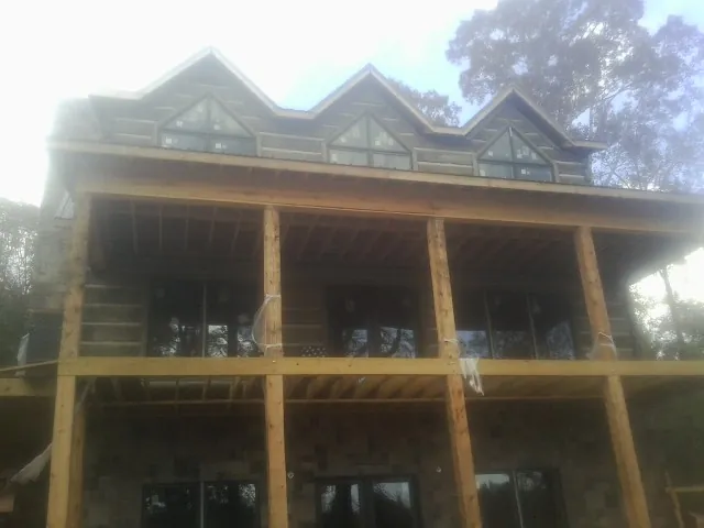 Dormers and porch framing on a large log home under construction — Roof Coating work by our crew in Monkton
