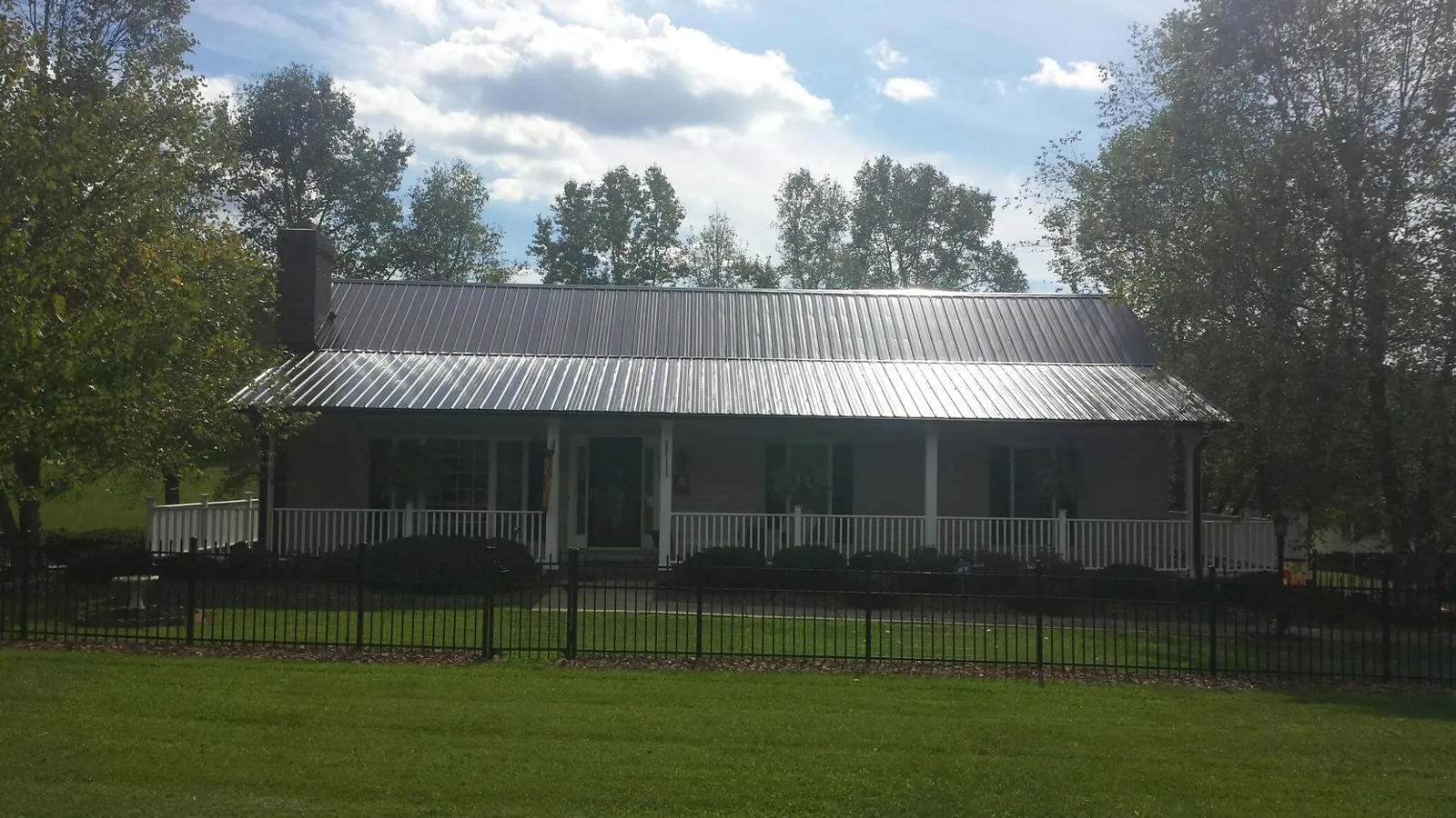 Gray metal roof on a brick ranch with a full width front porch — Gutter Guard Installation work by our crew in Monkton