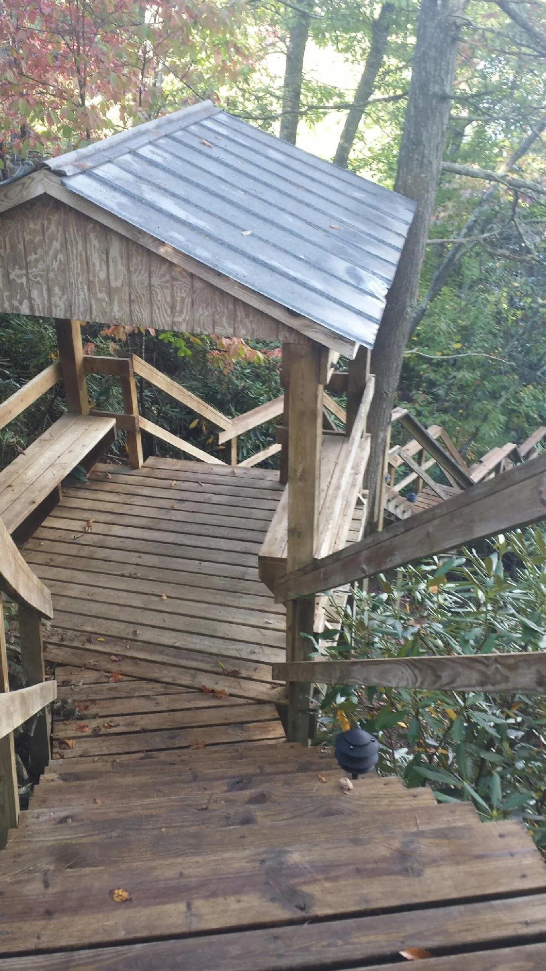 Metal roofed shelter over wooden steps on a wooded walkway — Skylight Repair & Installation work by our crew in Monkton