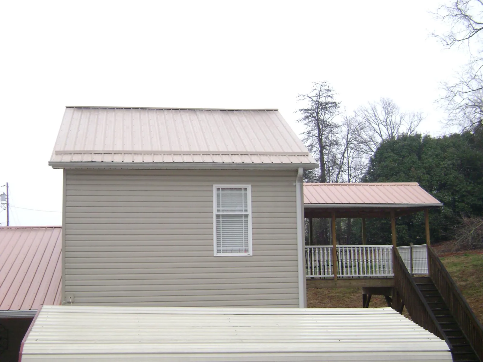 Tan metal roofs on a two story addition and attached porch, from a Roof Replacement job in Monkton