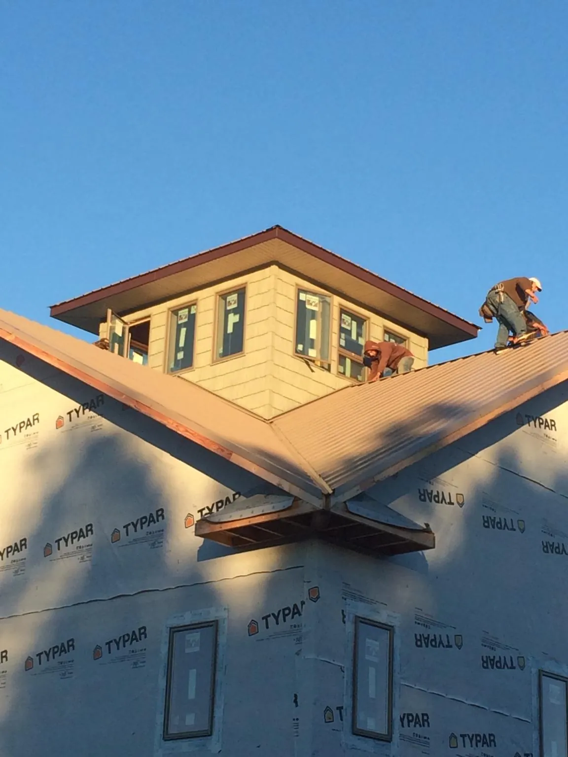 Roofers working around a rooftop cupola on a new metal roof at sunset — Roof Waterproofing in Monkton by Roofing Brothers